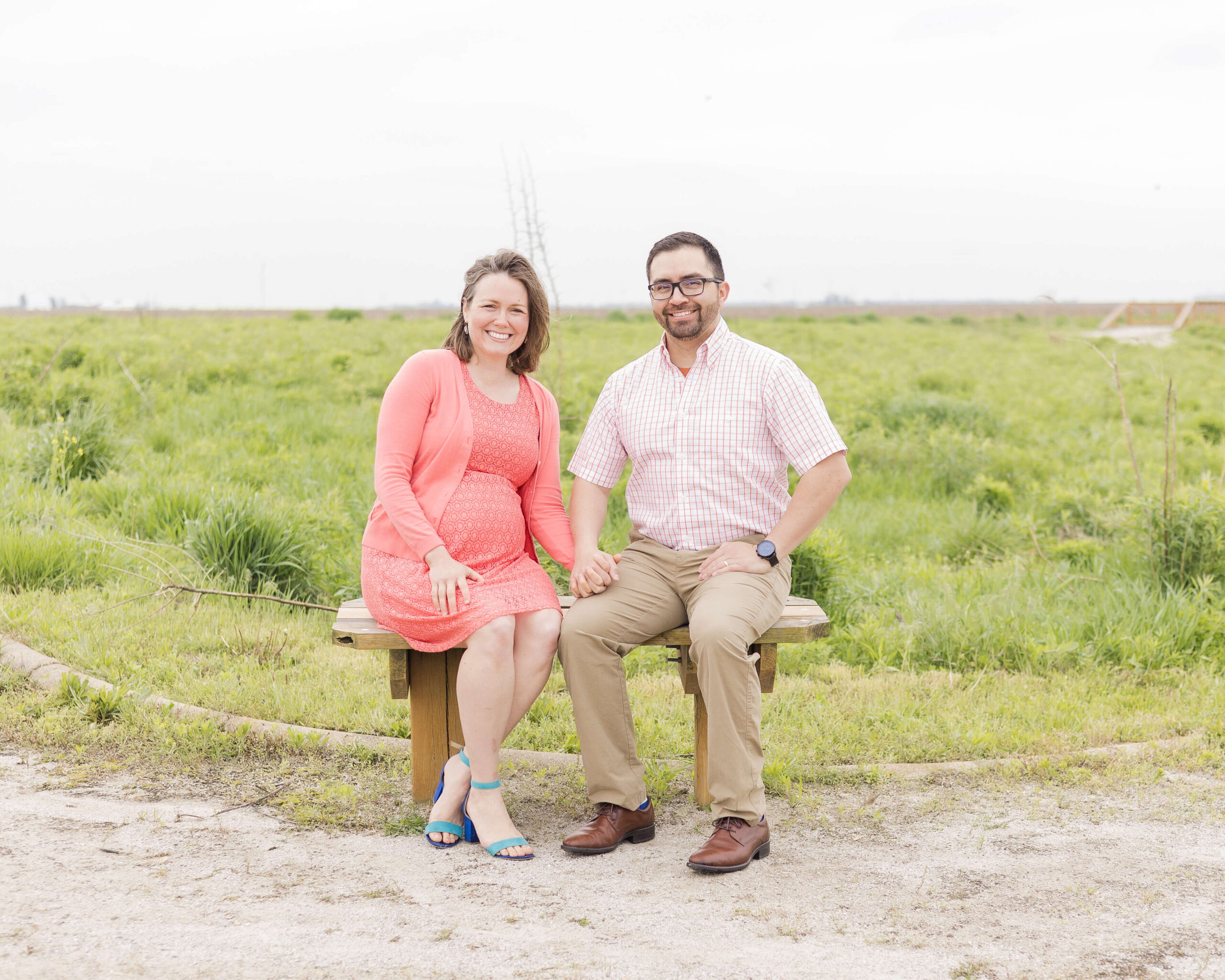 A pregnant couple sits on a park bench holding hands after meeting doulas in Springfield, IL