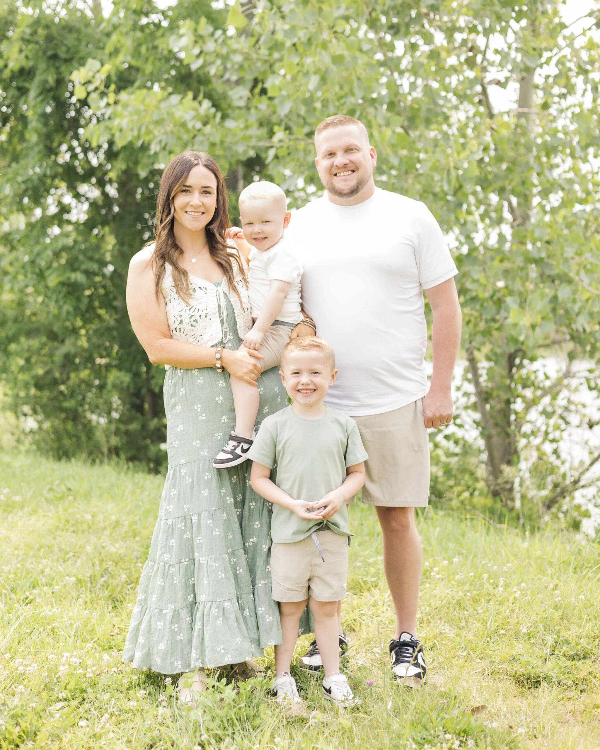 A mom in a green dress stands holding her toddler son on her hip with dad and older son standing with her by a pond during some kid-friendly things to do in Springfield, IL
