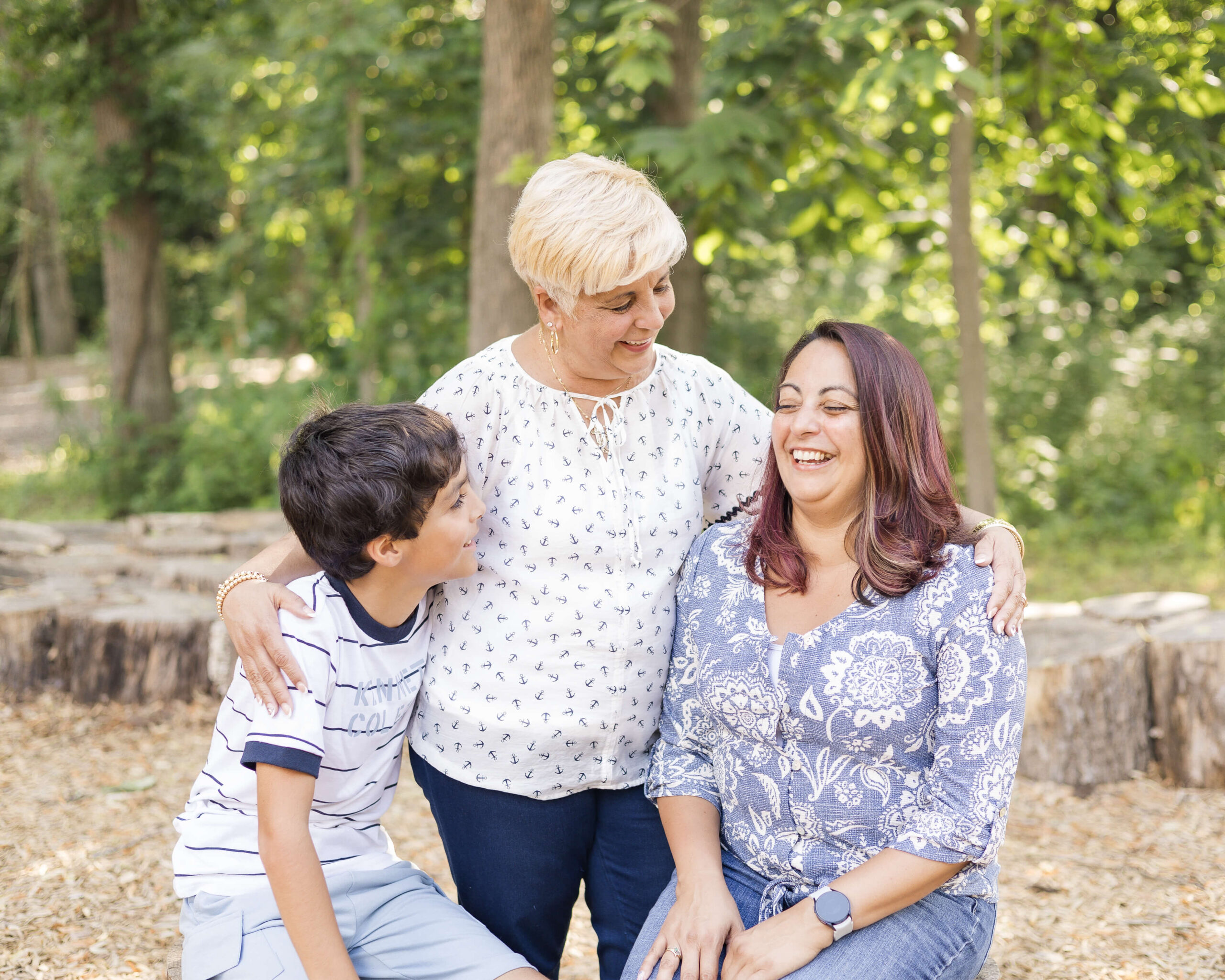 A young boy in a stripe shirt laughs with mom and grandma at one of the playgrounds in Springfield, IL