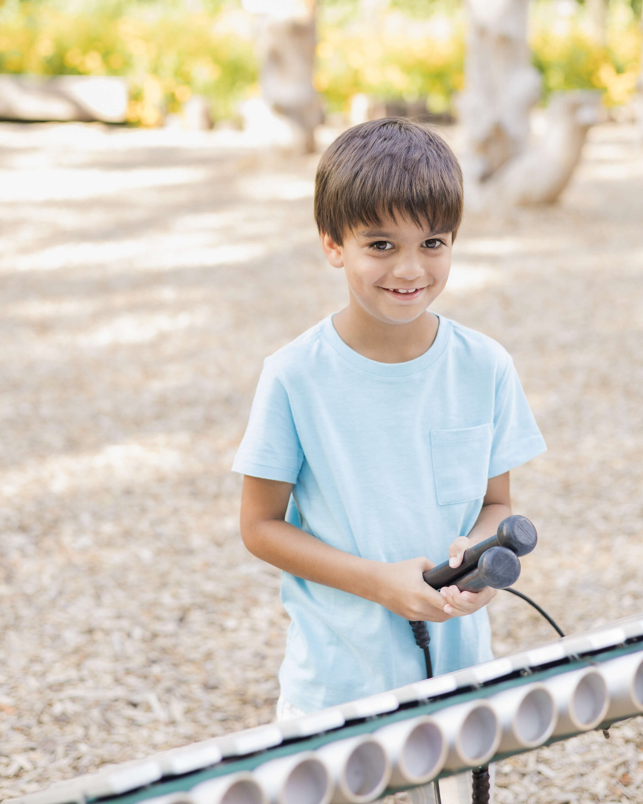 A young boy plays a playground marimba with a smile in a blue shirt after visiting lincoln historic sites in springfield illinois