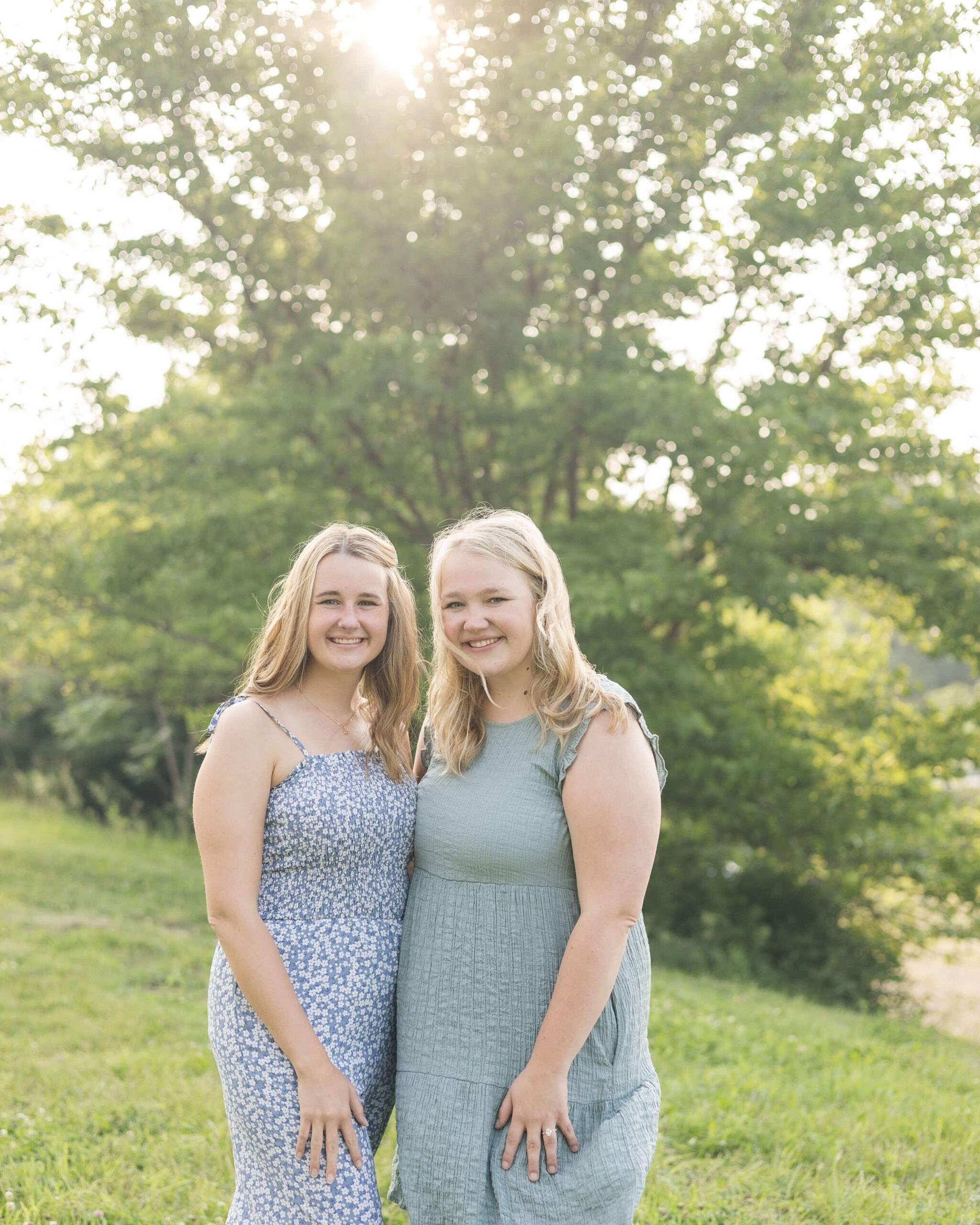 Sister in blue and green dresses smile while standing on a hillside at sunset after enjoying route 66 restaurant in springfield il