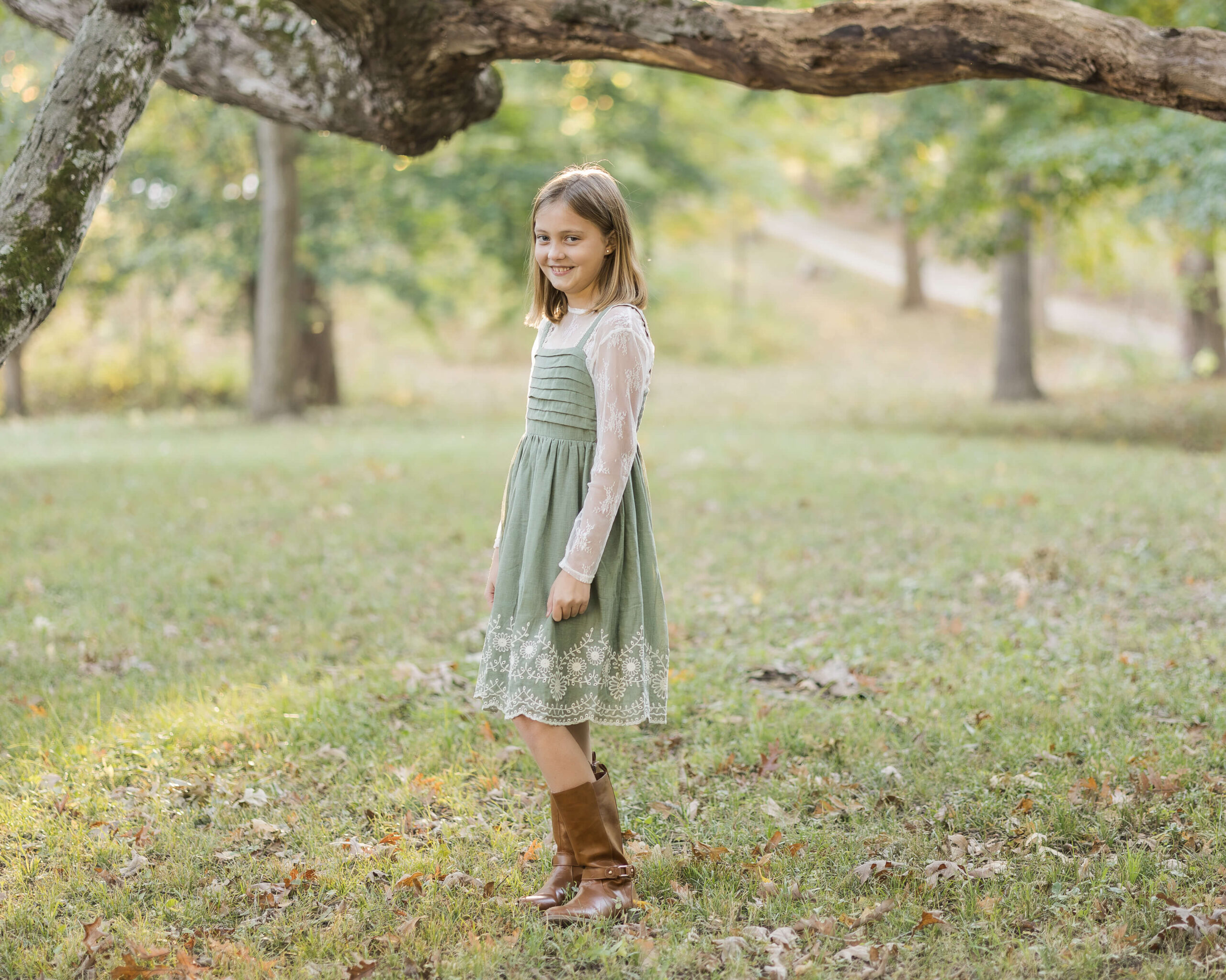 A young girl in a green dress walks in a park while smiling after attending great montessori schools in Springfield, IL