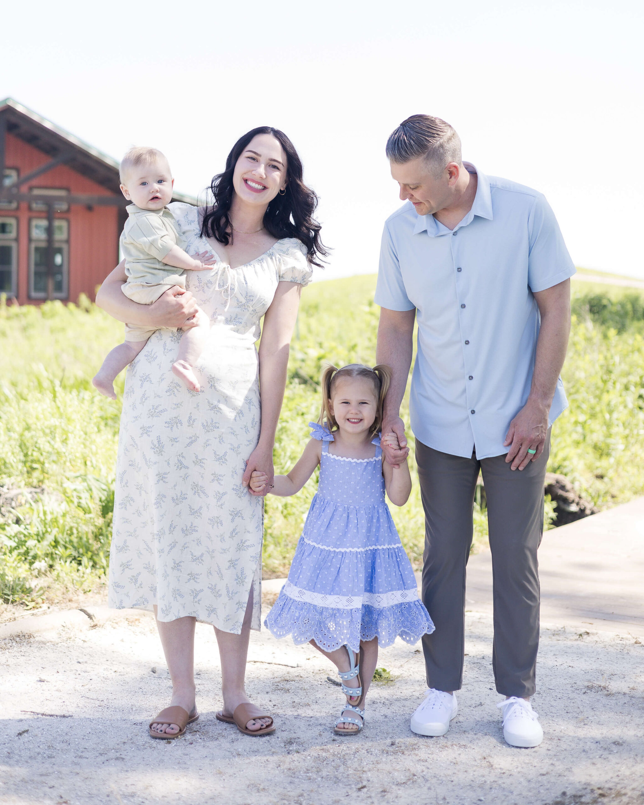 A mom carries a toddler on her hip while holding hadns with her toddler daugher and dad in a park path after easter brunch in springfield il