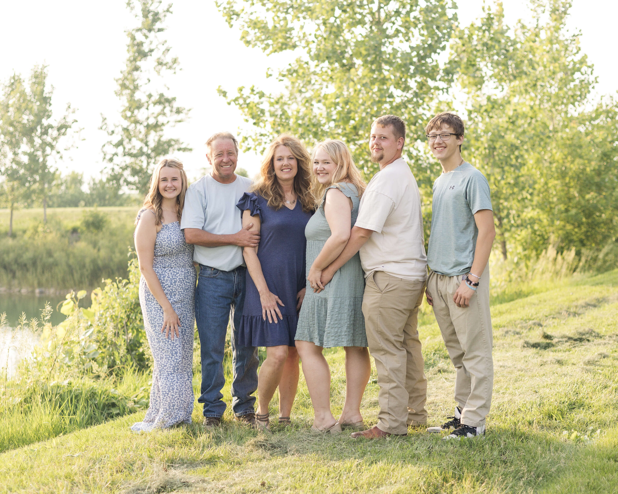 A happy family of adults stands in a park trail around a pond at sunset smiling after mother's day brunch in springfield il