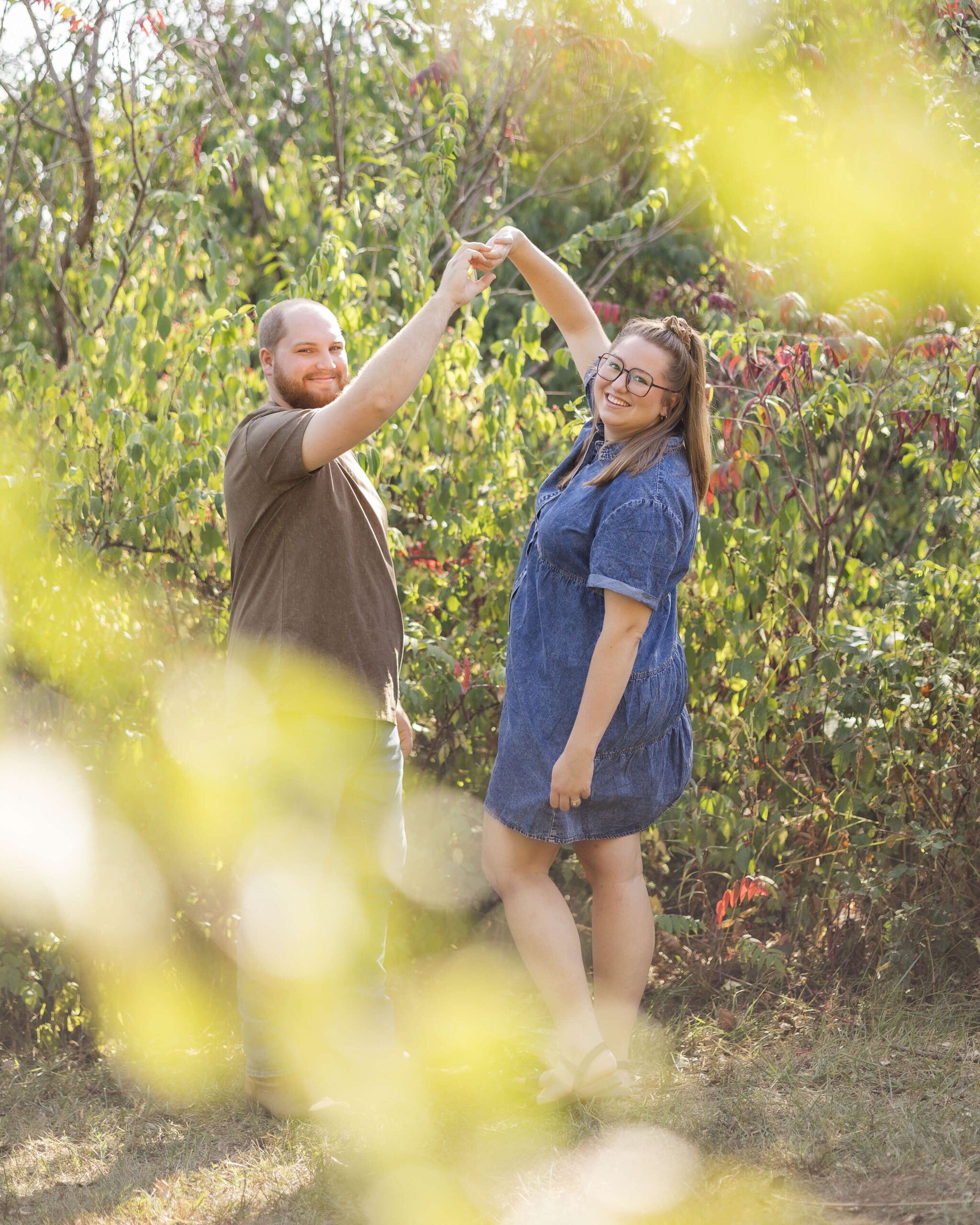A happy couple in denim and brown dance in a garden at sunset after some strawberry picking in central illinois
